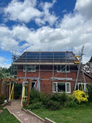 Rear of a semi-detached house with solar panels being fitted to the roof during installation